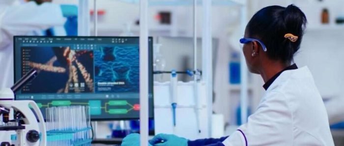 African woman biochemist researcher checking manifestations of vaccine working in modern equipped laboratory. Multiethnic doctors examining virus evolution using high tech researching diagnosis